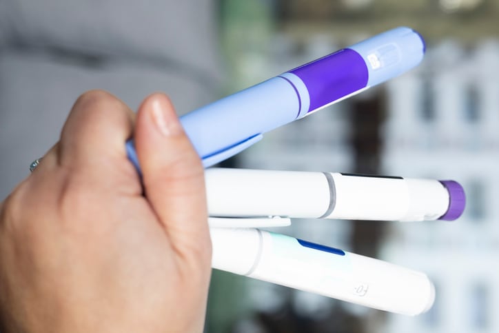 hand holding multiple injection pens, including semaglutide-based medications for different stages of treatment, used for weight loss and diabetes management. These GLP-1 receptor agonists help regulate appetite and metabolic health.