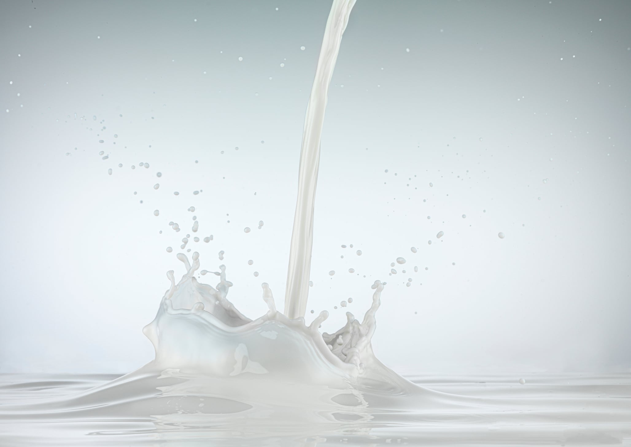 Poured milk splashing against white background