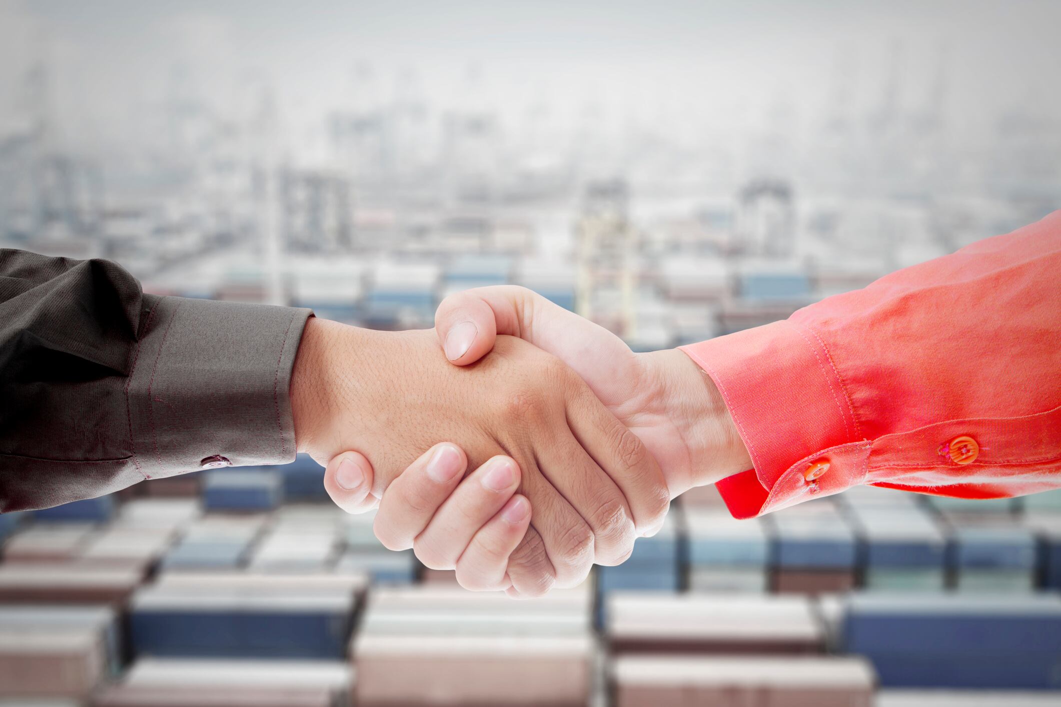 Business Handshake Over Shipping Containers Symbolizing Trade Agreement and Partnership