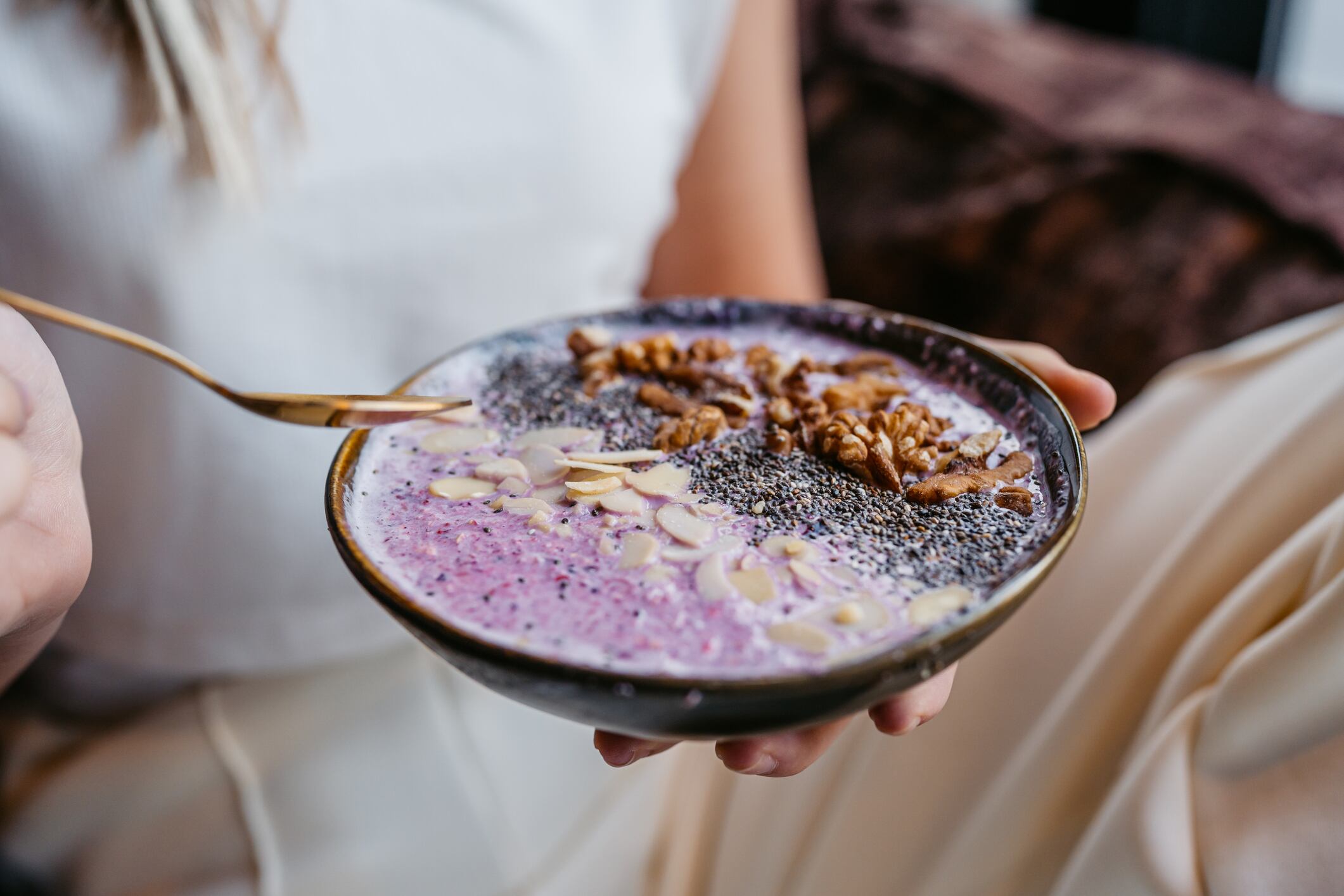 Young woman eating an Acai bowl in a café indoors.