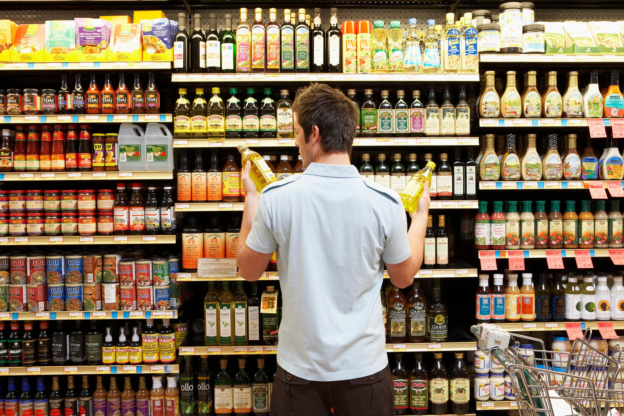Customer debating between oils in the grocery store.