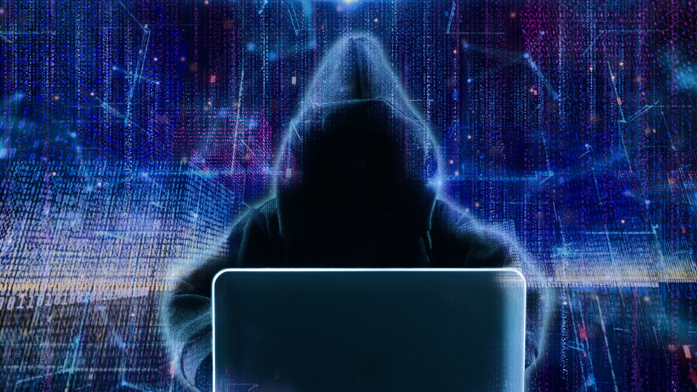 Hacker using laptop with abstract skull shape binary code.