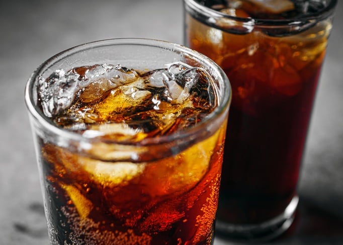 Cola soft drink with ice cubes, Close up of soda fizzy drink in Cold glass on gray background