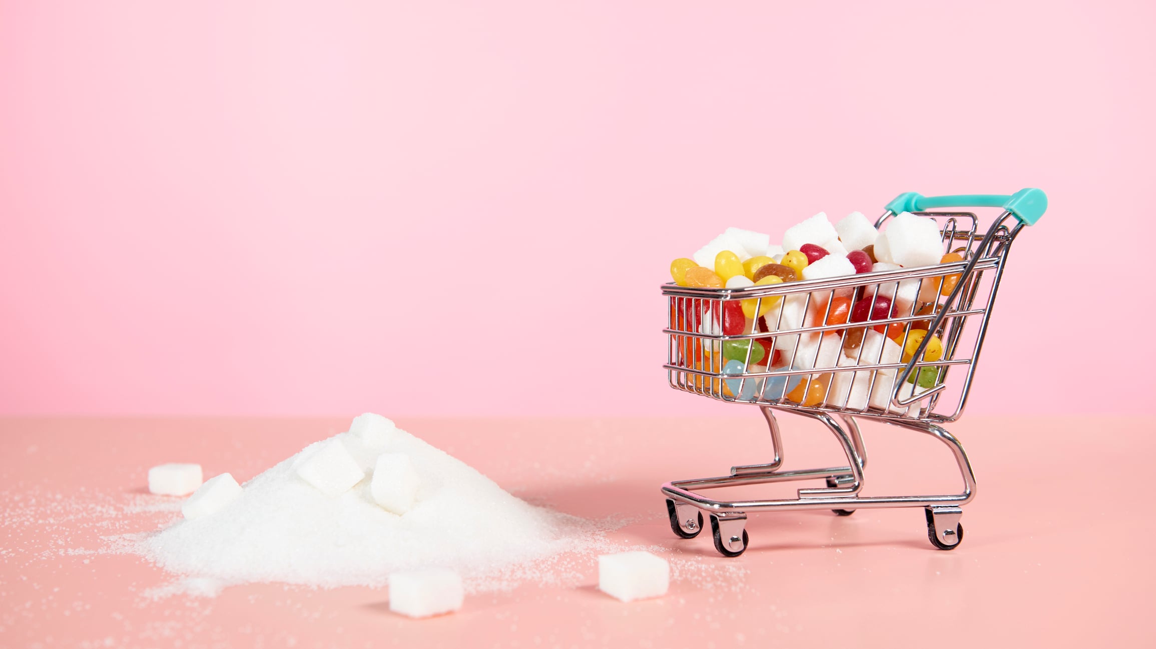Supermarket trolley with sweets and pile of sugar next to it