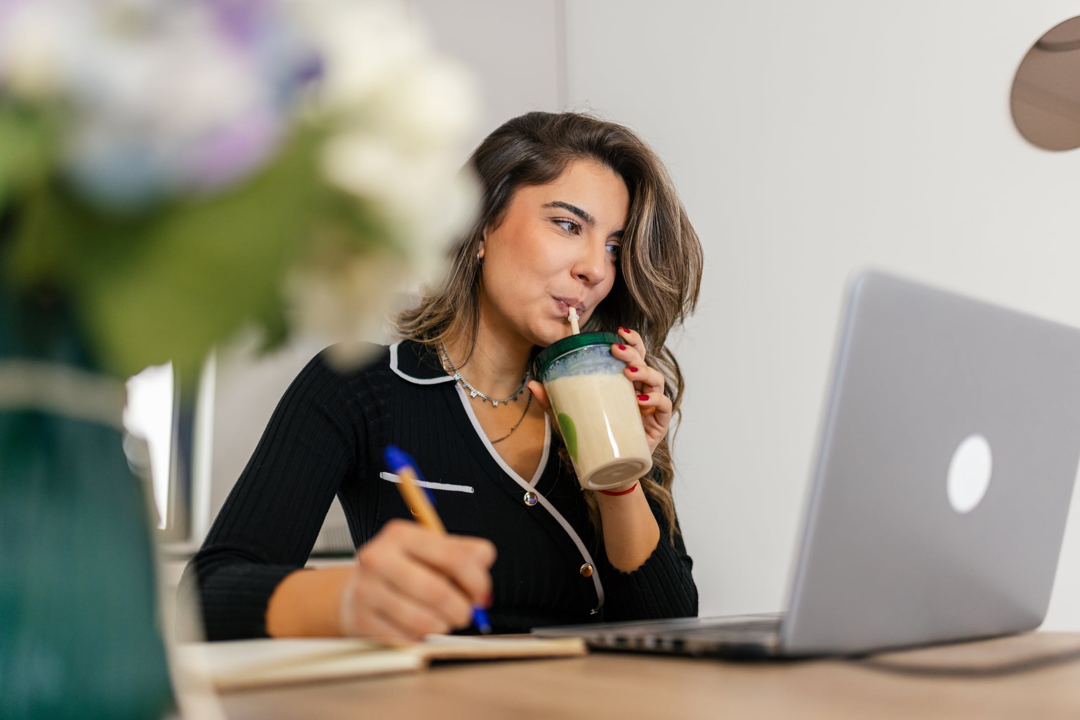 Woman sitting at the table, drinking protein smoothie